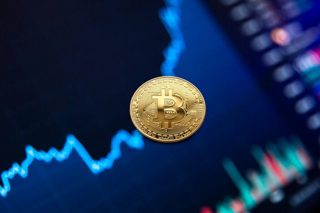 pexels-photo-7788009-7788009 A gold Bitcoin coin against a backdrop of a digital financial chart, symbolizing cryptocurrency trading.