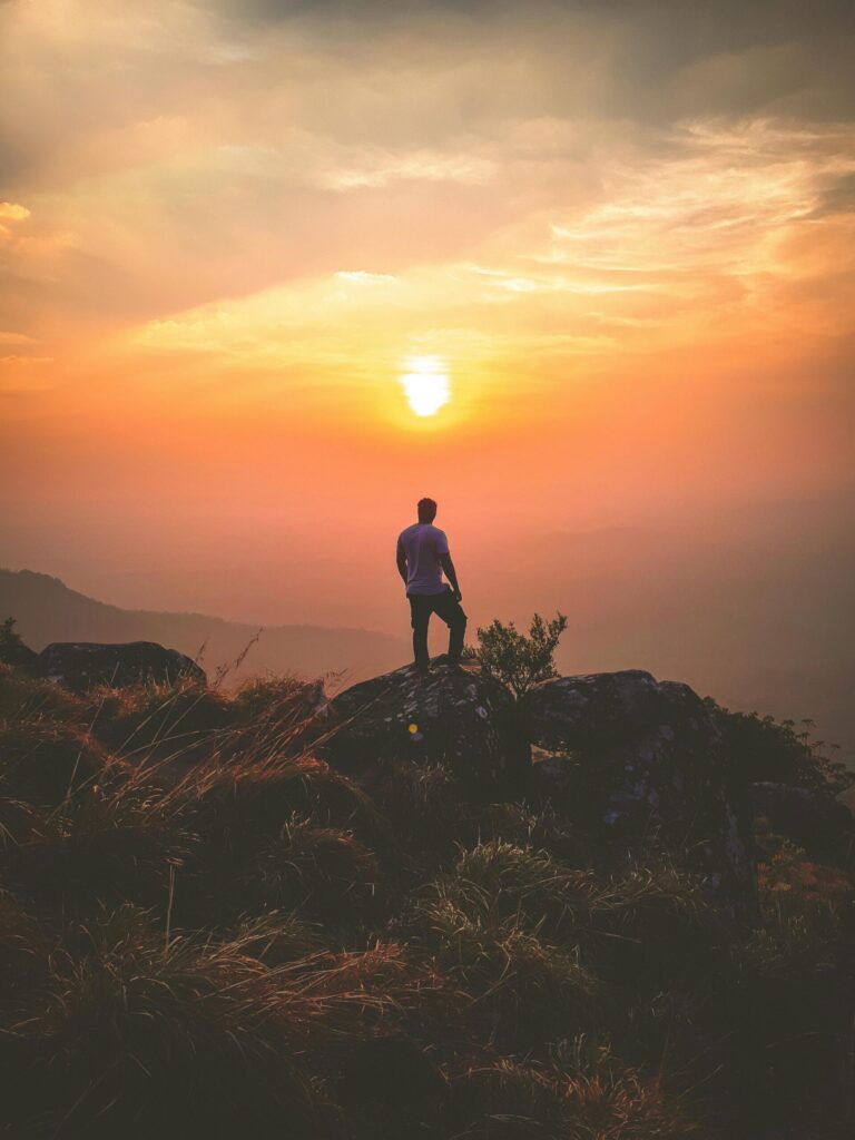 pexels-photo-906531-906531 A lone hiker admires a stunning sunset view from Ponmudi Peak, creating a serene landscape scene.